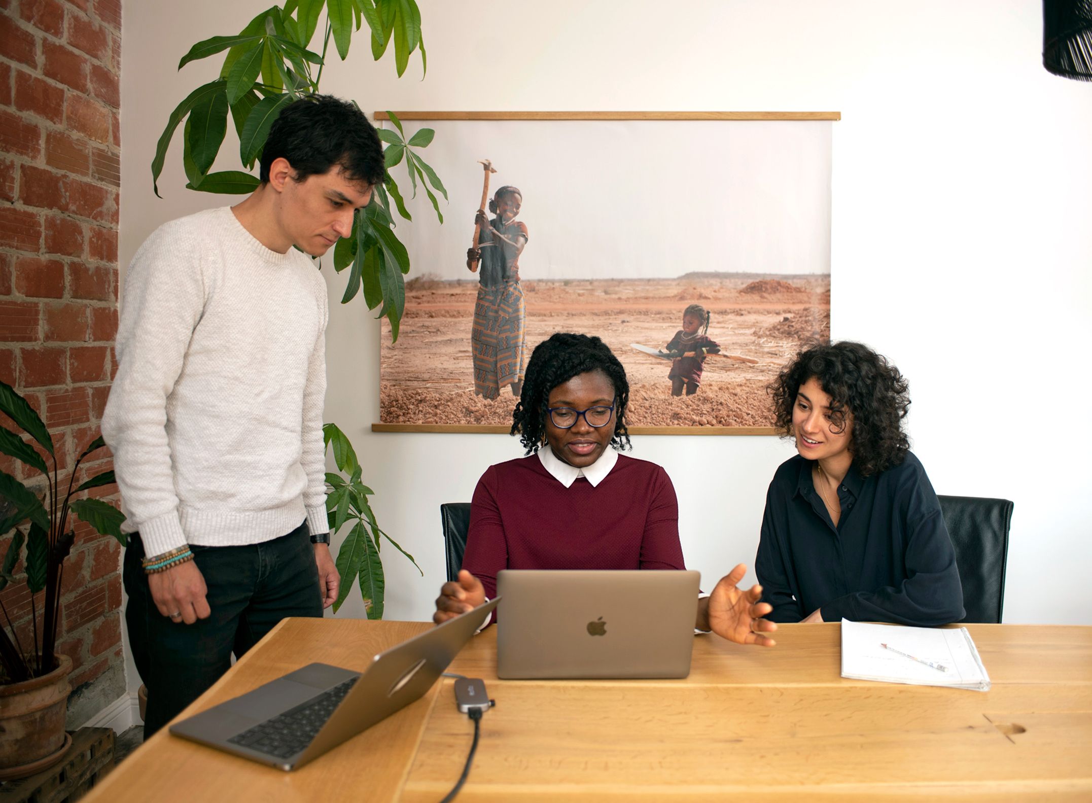 3 diverse colleagues discuss at a laptop 