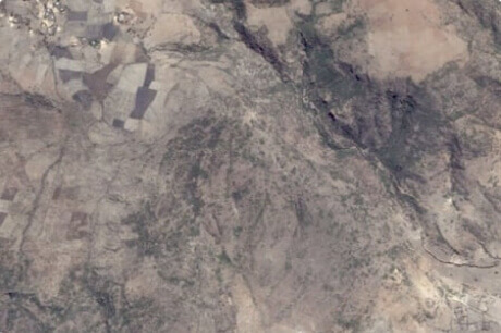 Satellitenbild einer trockenen, leblos aussehenden Landfläche vor der Baumpflanzung.